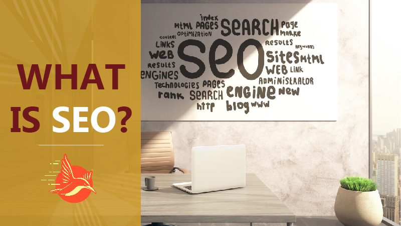 A desk with a laptop and the words “What is SEO?” written on the wall behind it. Optimizing Listings with SEO