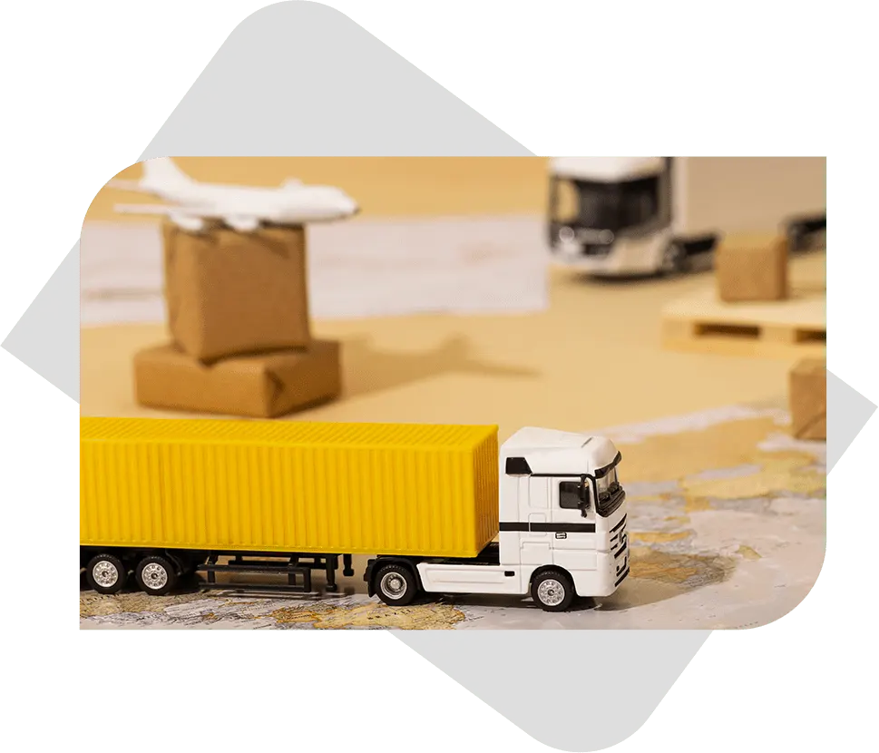 A small toy container truck placed on a map table, with a toy plane in the background, symbolizing global logistics and shipping.